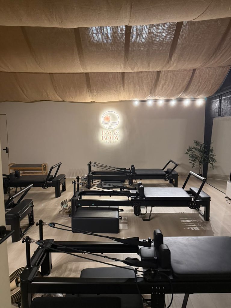 Bay & Body Studios reformer studio with black Pilates reformers and a linen-draped ceiling