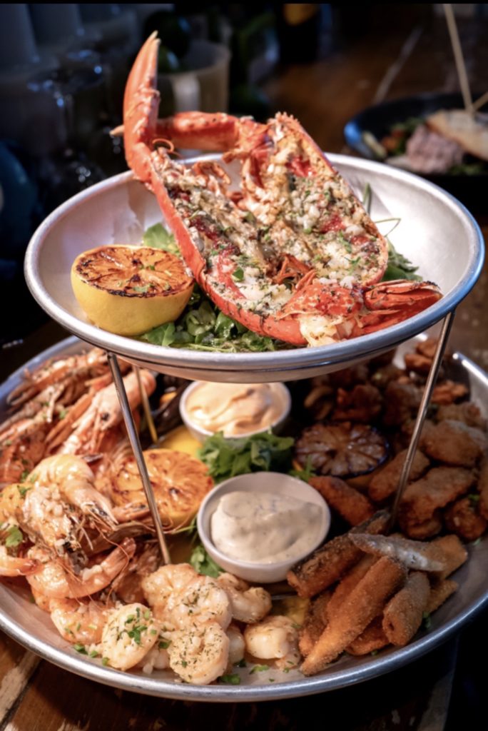 Tiered seafood platter with lobster, prawns, fried fish and lemon, served with dips